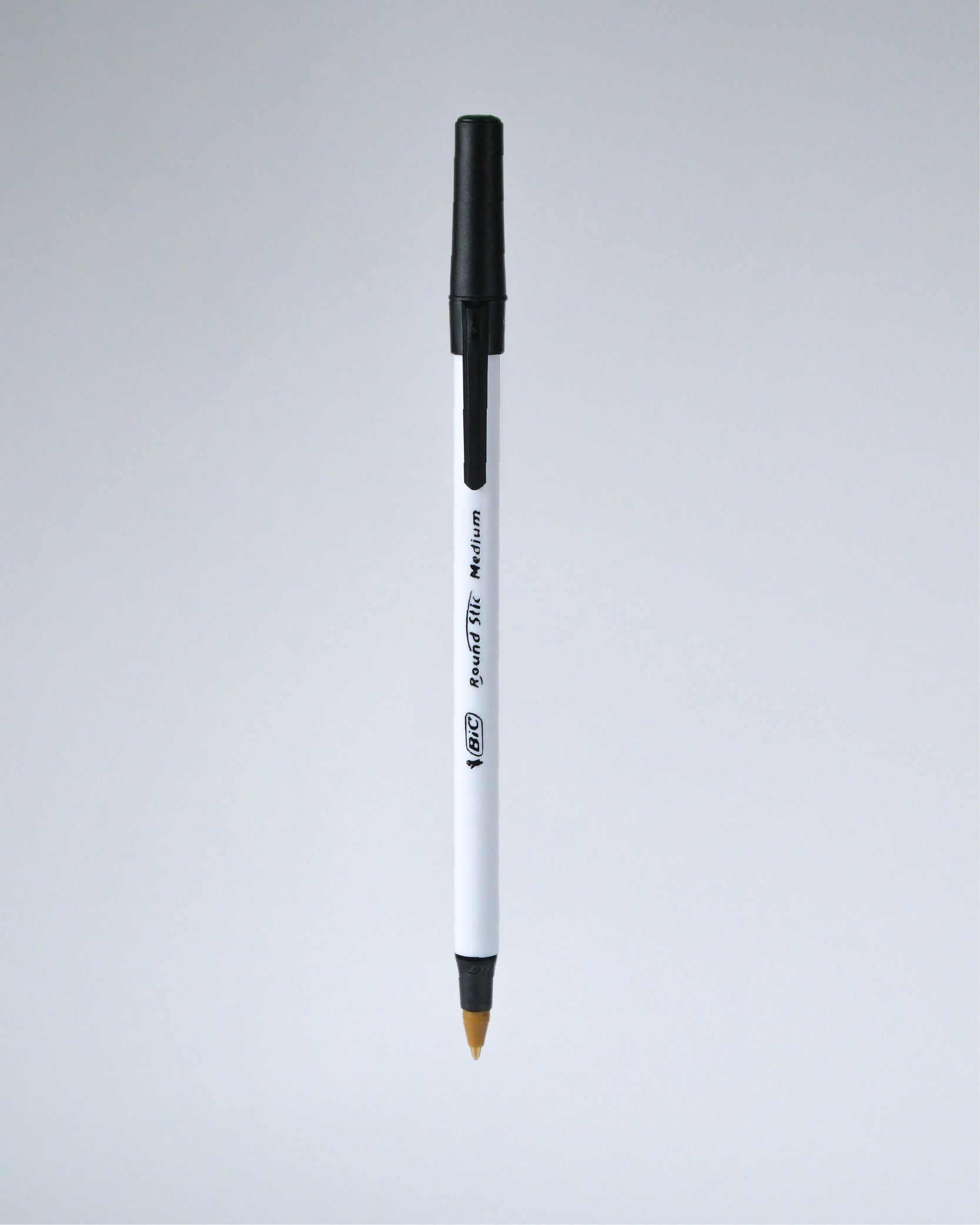 A single white and black ballpoint pen with a gold-tipped tip, shown vertically against a light gray gradient background.