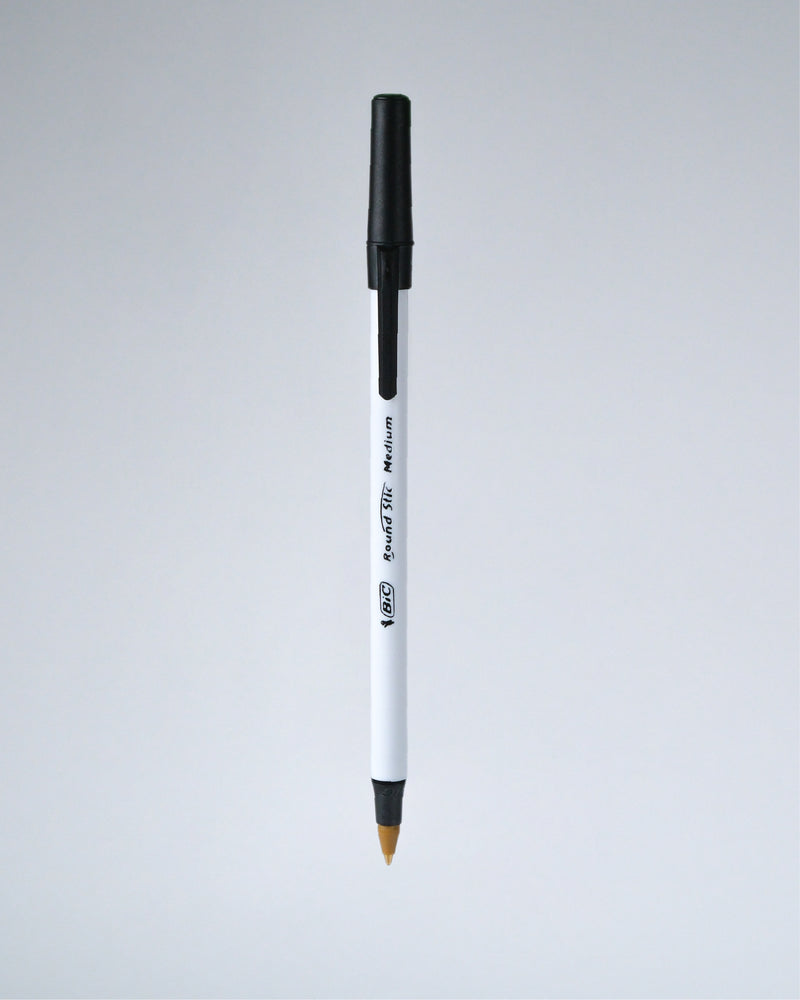 A single white and black ballpoint pen with a gold-tipped tip, shown vertically against a light gray gradient background.