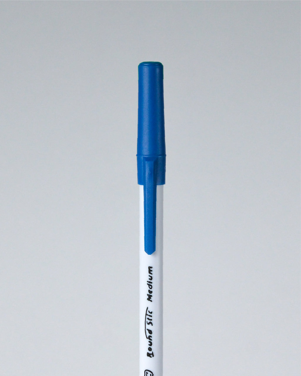 A single blue and white marker pen shown vertically against a light gray background. The barrel is white with black text reading 'Brush STI Medium', and the cap and top section are blue.