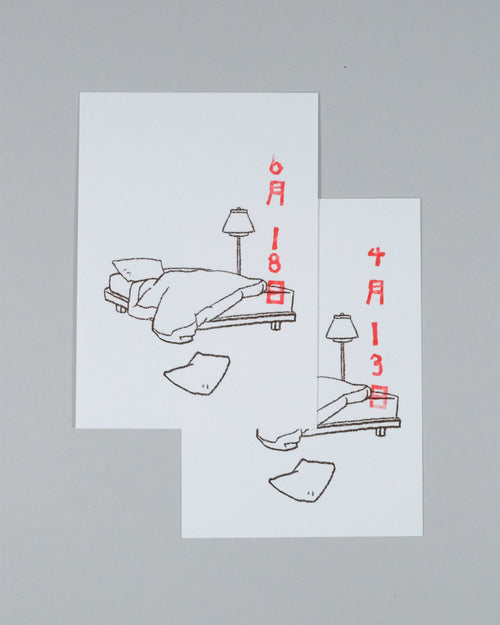 Two white art prints with minimalist line drawings of a bed, lamp, and clothing items, annotated with red Japanese dates, displayed on a neutral gray background.