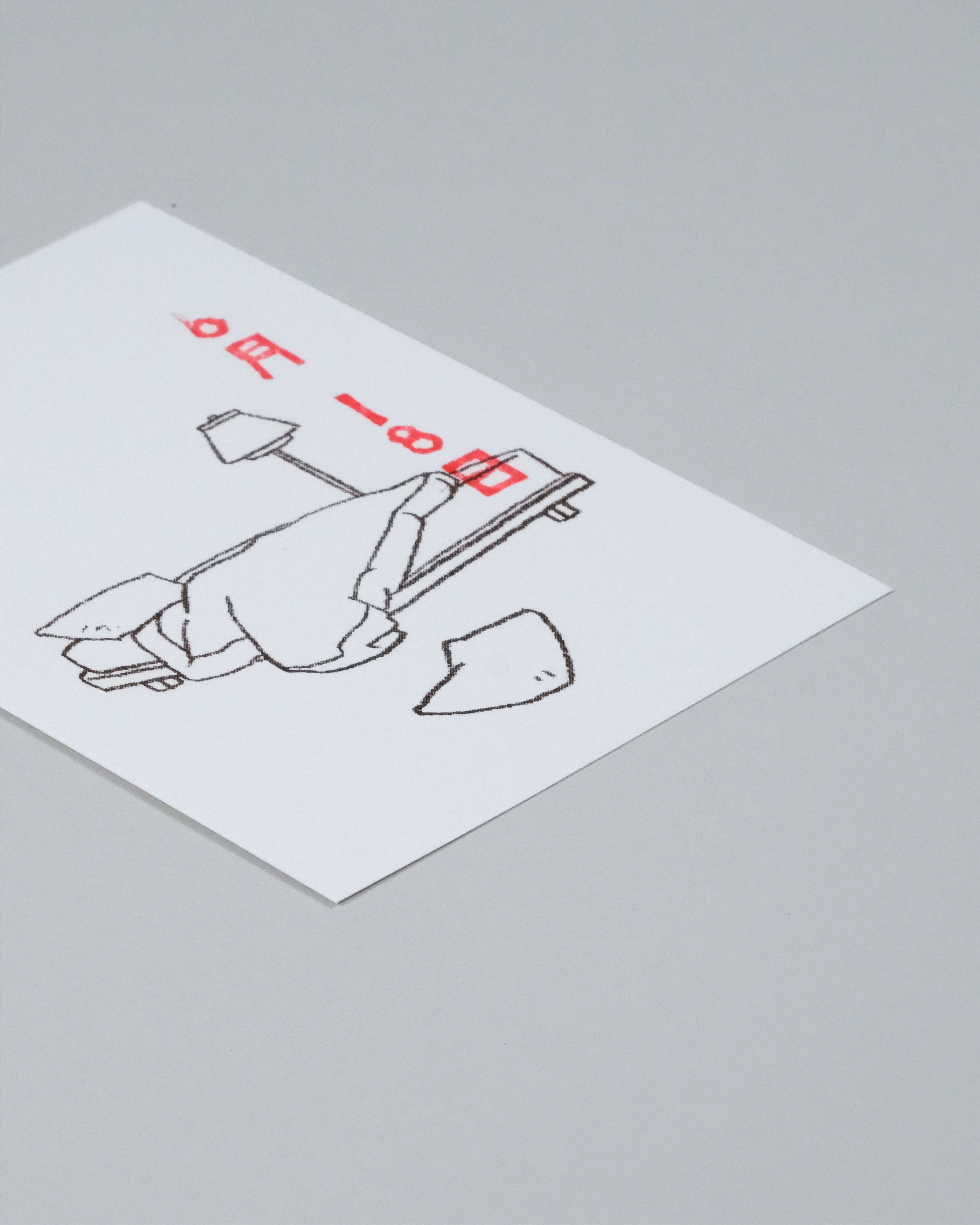 A square white art print or postcard featuring a minimalist black line drawing of a person lying on a beach chair with red text, photographed on a neutral gray background.