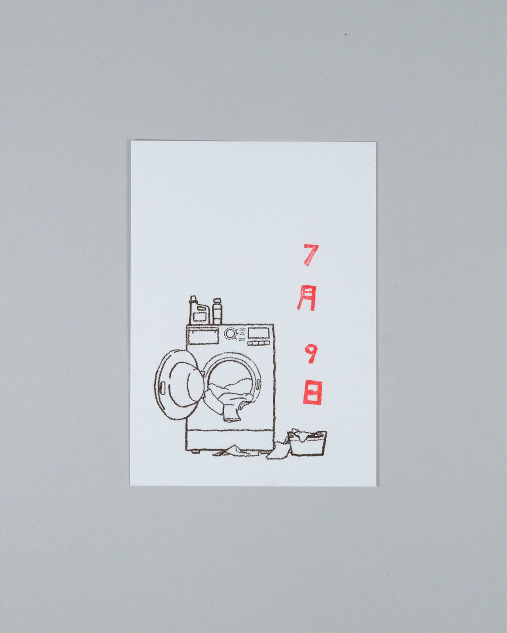 A minimalist art print featuring a black line drawing of a washing machine with red Japanese characters on a white rectangular card, set against a neutral gray background.