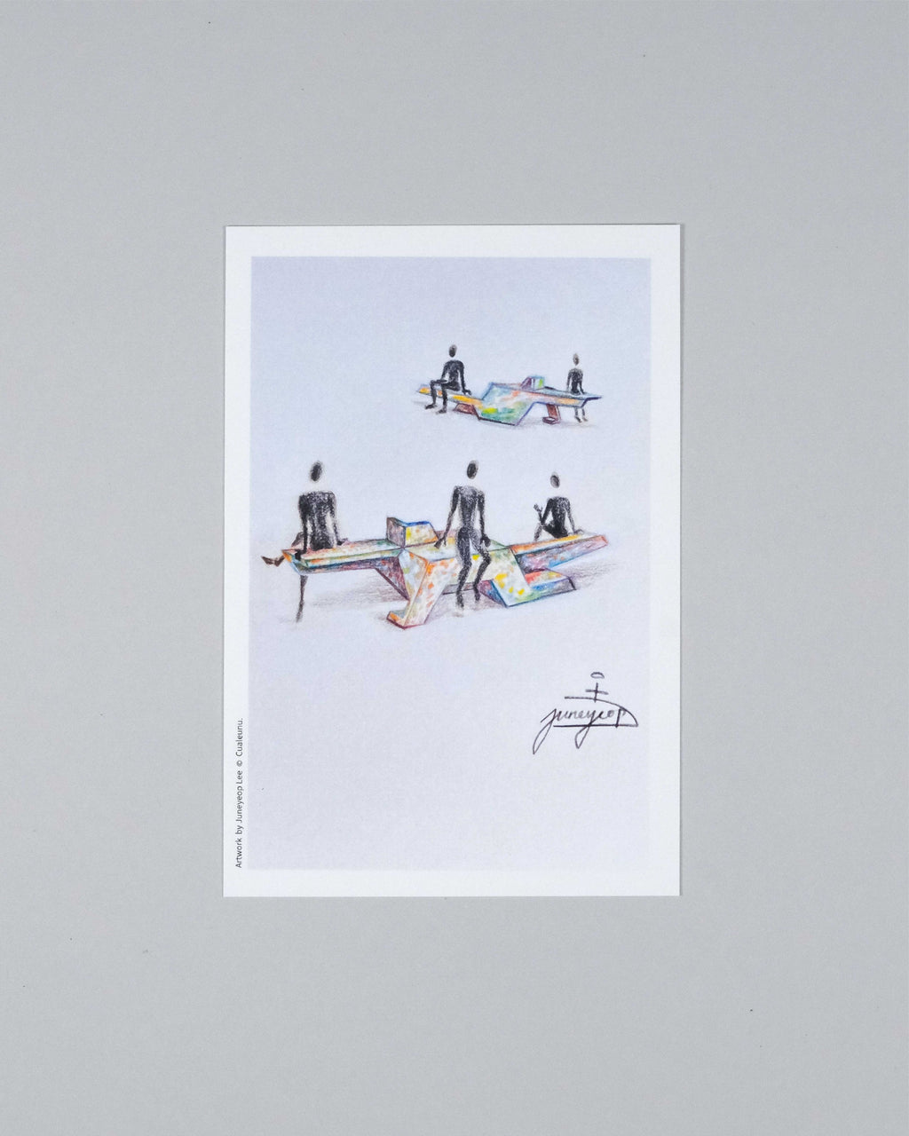 A framed art print featuring a minimalist illustration of several figures standing around colorful, geometric tables on a light background, displayed against a neutral gray wall.