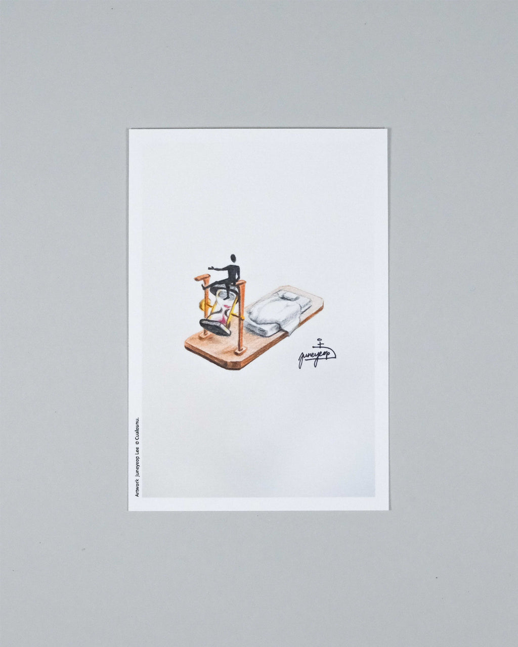A minimalist art print featuring an isometric illustration of a person riding a bicycle on a skateboard, printed on a white sheet of paper and displayed against a neutral gray background.