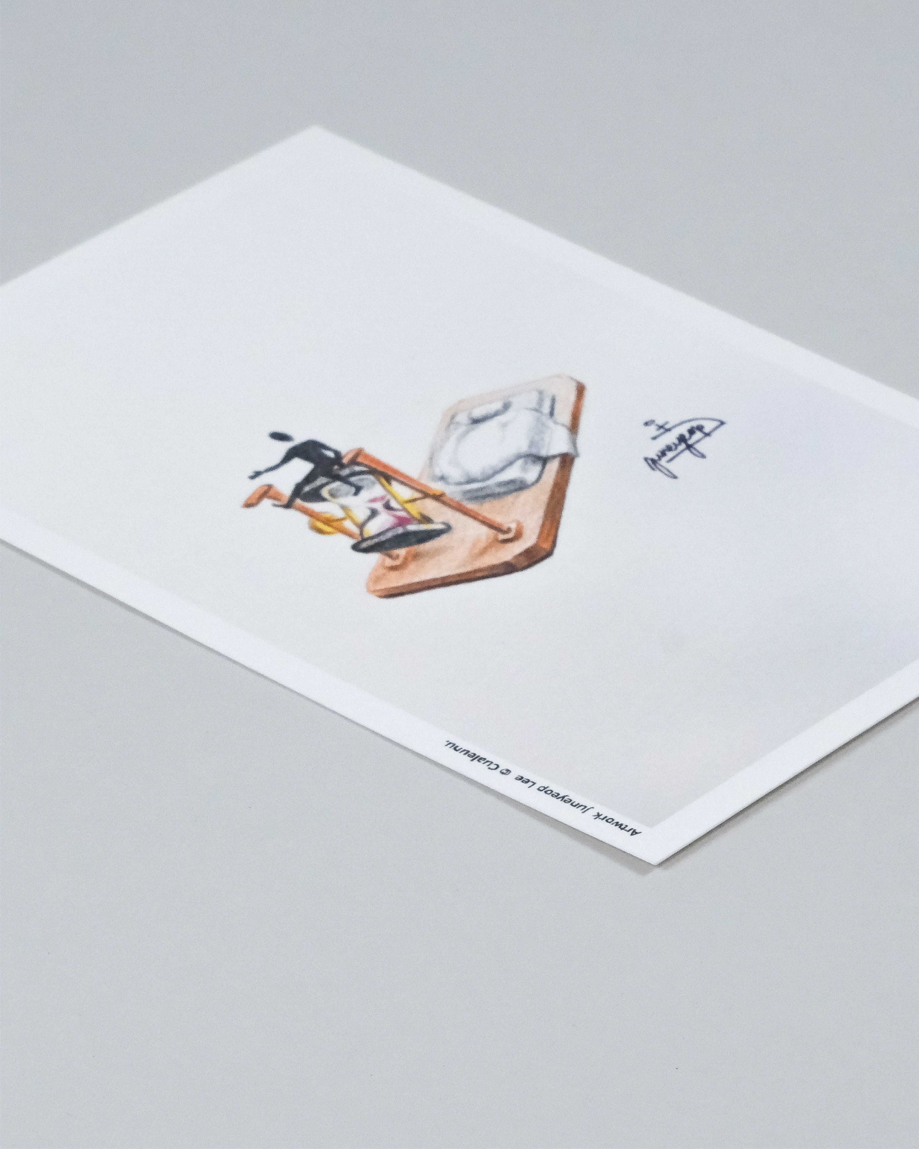 A minimalist art print on white paper, featuring a small illustration of a figure with a bicycle and a bicycle frame, photographed on a neutral gray background.