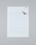 A single lined notepad sheet with a white background and thin gray horizontal lines, photographed on a plain light gray surface. A faint brown coffee stain is visible near the top right corner of the pad.