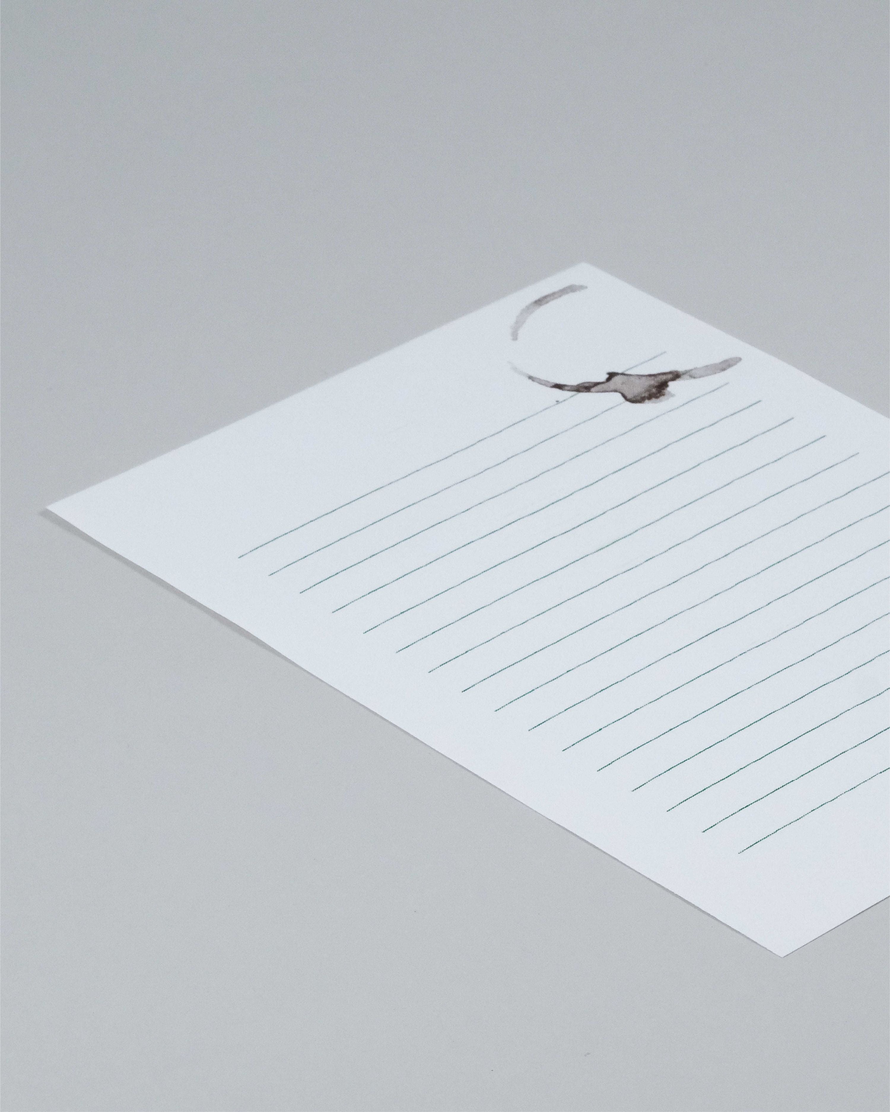 A white lined notepad sheet with a small gray bird illustration in the top right corner, photographed on a light gray background.