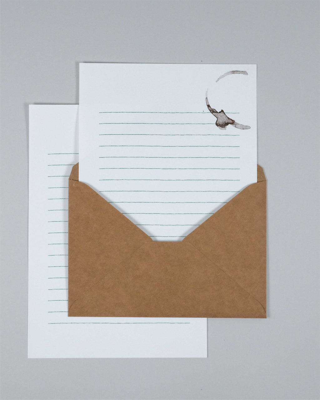 A kraft brown envelope with a white lined letterhead card partially pulled out, photographed on a plain light gray background.