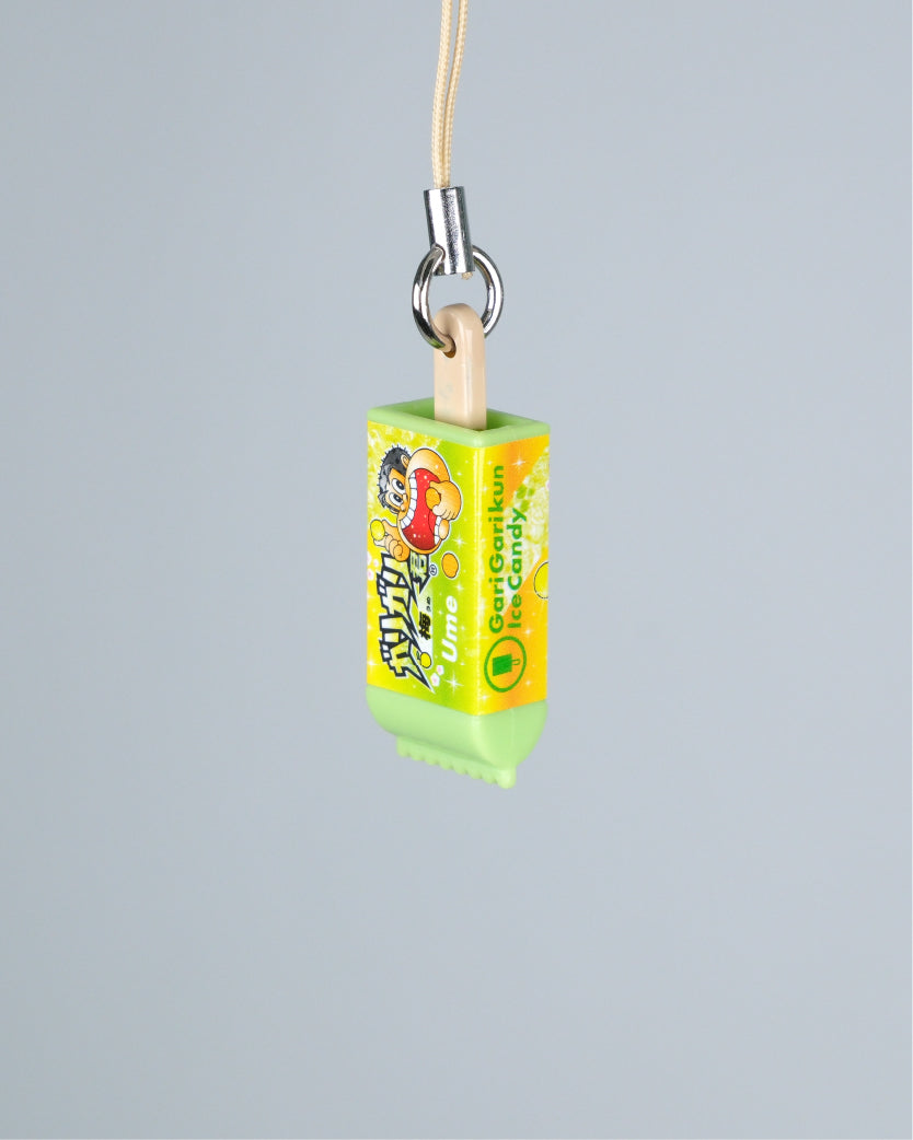 A small novelty keychain or phone charm shaped like a popsicle stick, with a light wood stick, silver metal ring, and beige cord. The wrapper is bright yellow and green with cartoon graphics and the text 'Gorocanica IceCandy' visible on the side.