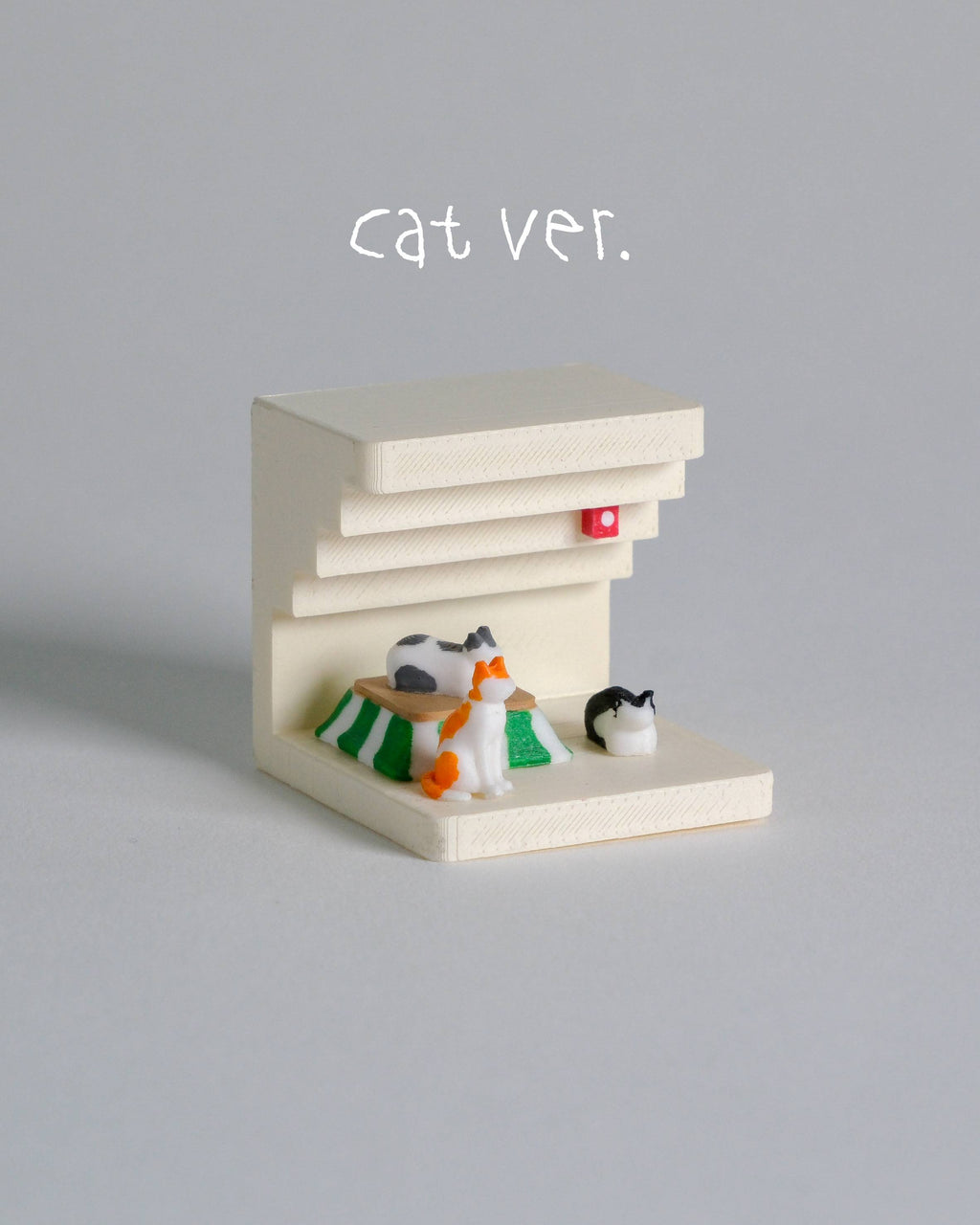Small model of a cat cafe with three cat figurines on a gray background