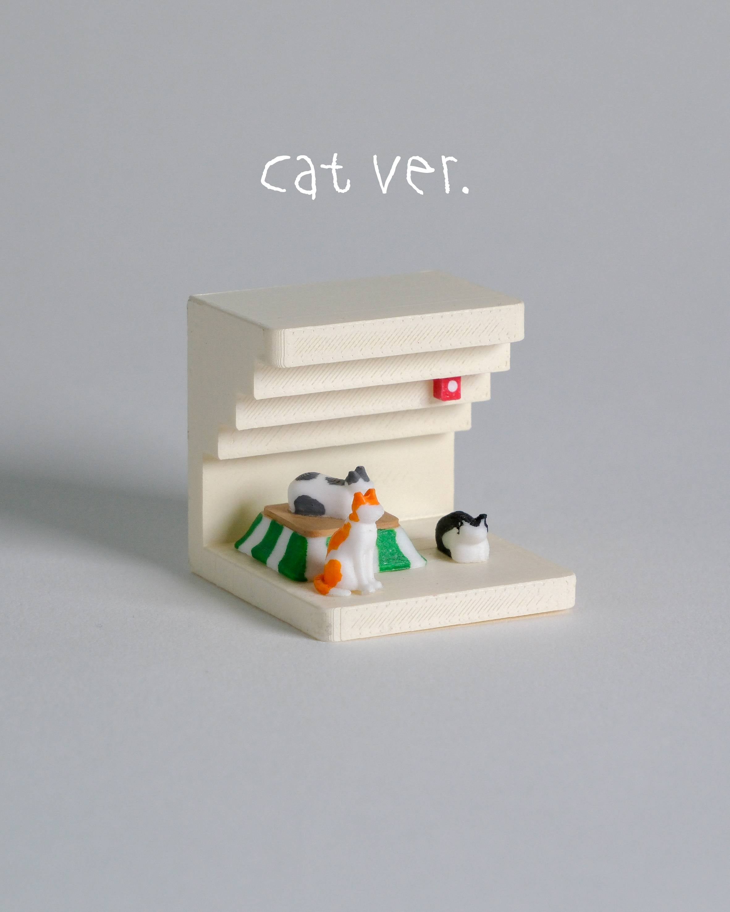 Small model of a cat cafe with three cat figurines on a gray background
