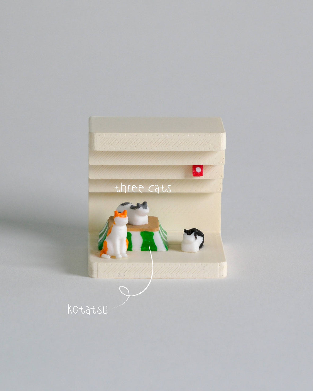 Miniature model of a cat tree with three toy cats on a gray background