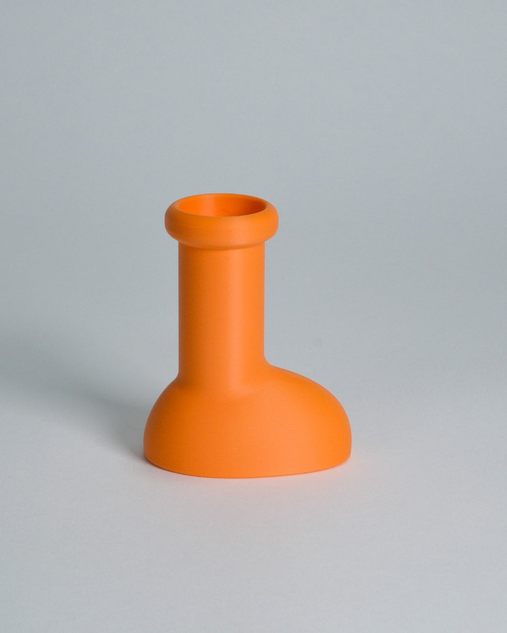 A bright orange silicone bottle stopper or small vase with a wide rounded base and cylindrical neck, shown on a neutral light gray background.