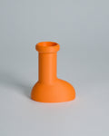A bright orange silicone bottle stopper or small vase with a wide rounded base and cylindrical neck, shown on a neutral light gray background.